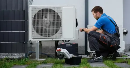 Technician servicing outdoor air source heat pump unit